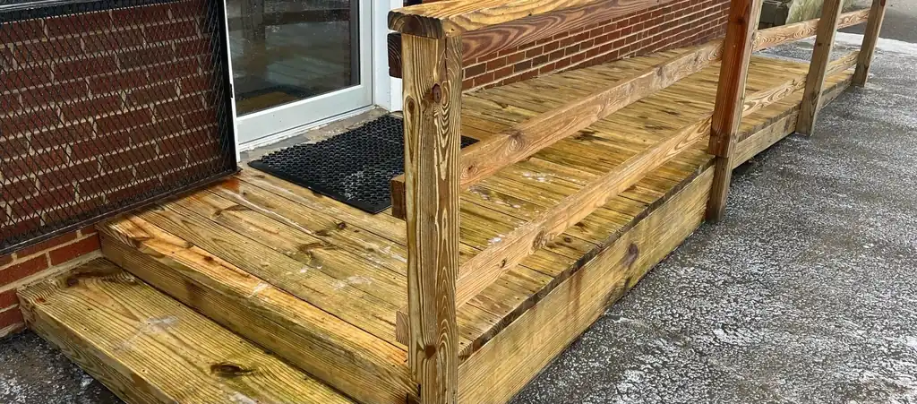 A wood deck ramp and railing washed back to warm golden wood