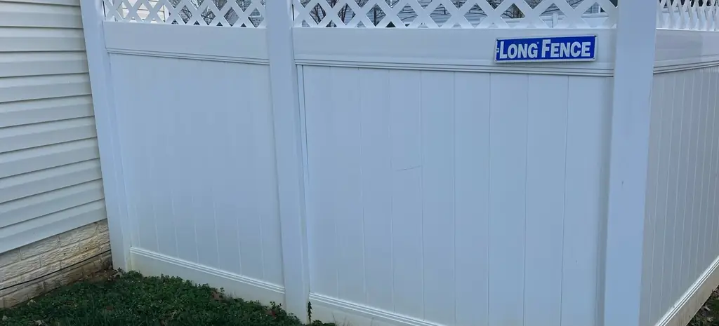 White vinyl lattice-top fence washed bright after mildew was lifted off the panels