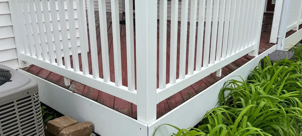 White porch railing on a brick base, clean along every spindle