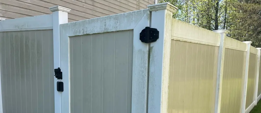 Tan vinyl privacy fence yellowed with grime before washing