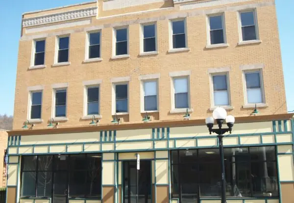 Tan brick three-storey commercial building with an awning and a lamp post
